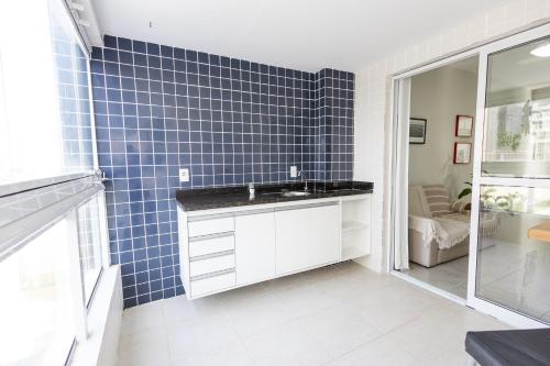 a bathroom with a sink and a blue tiled wall at Itanhaém Praia & Mar in Itanhaém