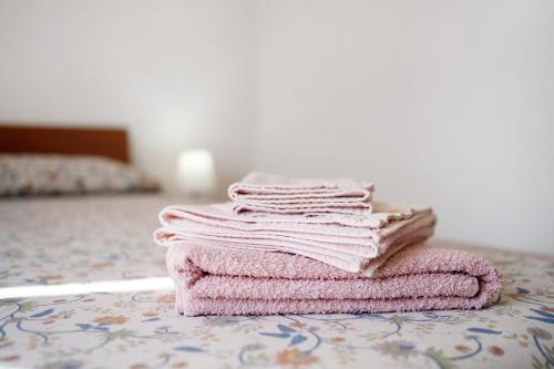 uma pilha de toalhas cor-de-rosa sentadas numa cama em Home Gilda em Imperia