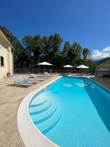 a large swimming pool with chairs and umbrellas at Le Boccede Country House B&B in Villa Minozzo