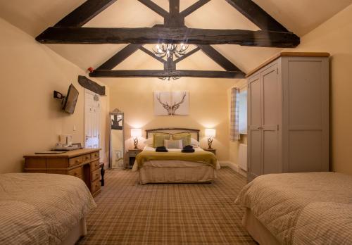 una camera con due letti e un soffitto con travi a vista di The Moon Inn at Stoney Middleton a Stony Middleton