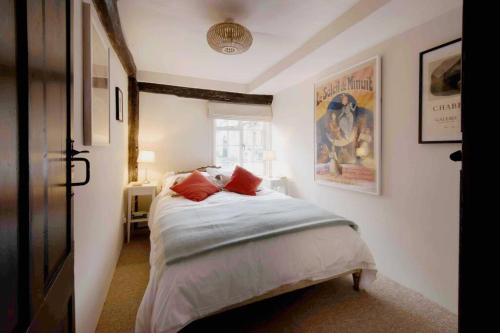 a bedroom with a bed with red pillows on it at Characterful apartment in the heart of Petworth in Petworth
