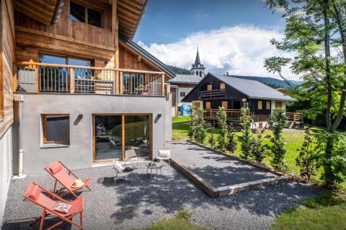 a house with a patio and red chairs in front of it at Chalet Mevi - OVO Network in Crest-Voland