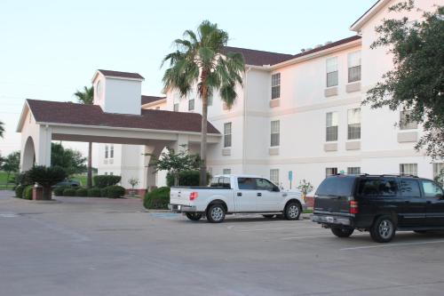 un camion blanc garé dans un parking en face d'un bâtiment dans l'établissement Motel 6-Rosenberg, TX, à Rosenberg