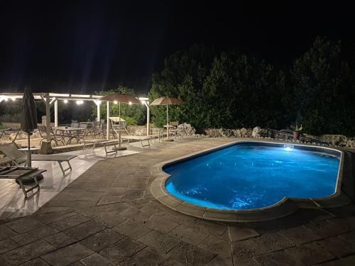 a swimming pool at night with tables and umbrellas at Agriturismo Masseria Saittole in Carpignano Salentino