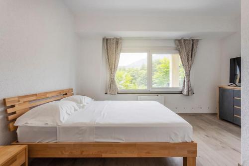 Un dormitorio con una gran cama blanca y una ventana en Casa Magging un oasi nel verde, en Locarno
