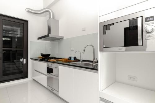 a white kitchen with a sink and a microwave at The LINs House in Guiren