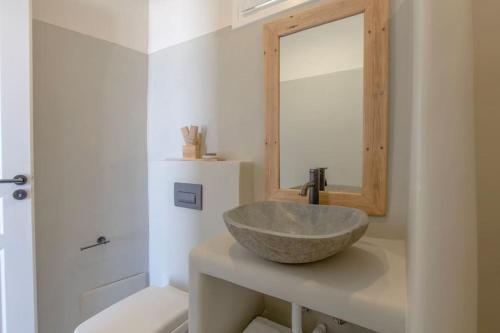 y baño con lavabo de piedra y espejo. en Lyra Sunset Suite en Kampos Paros