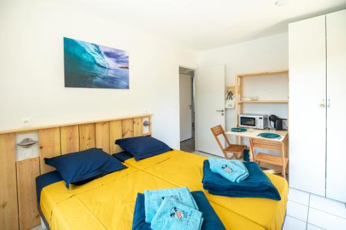 1 dormitorio con cama amarilla y almohadas azules en un Air de Repos, en Vieux-Boucau-les-Bains