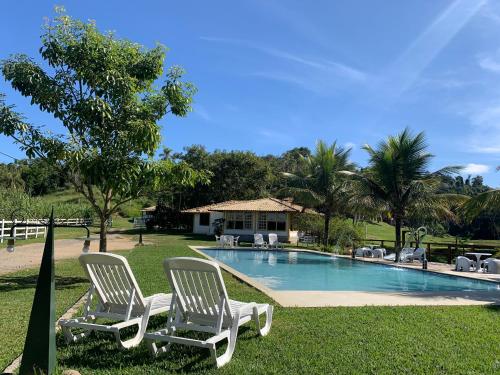 dos sillas blancas sentadas junto a una piscina en Hotel Fazenda Bom Retiro, en Quatis