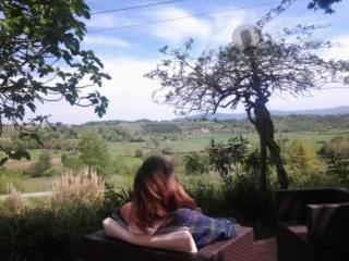 a woman sitting on a table looking out of a window at Fattoria di Mugnano in Colle Val D'Elsa