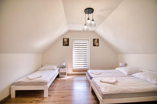 2 łóżka w sypialni na poddaszu z oknem w obiekcie HOUSE OF ENERGY - Zator Przeciszów w mieście Przeciszów