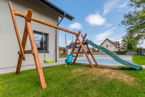 a playground with a slide and a swing at Flatbook Apartamenty - Mikoszewo Dudówka in Mikoszewo