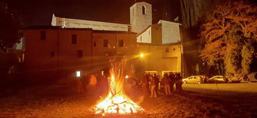 a group of people standing around a fire at night at B&B dell'Osteria in SantʼAnatolia di Narco