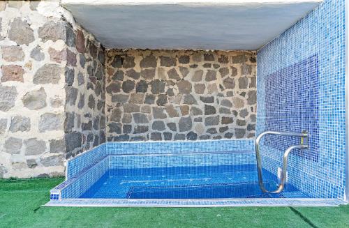 Habitación con bañera de azulejos azules y pared de piedra. en Apartamentos Dulcemar Frente al Mar con zona SPA, en San José