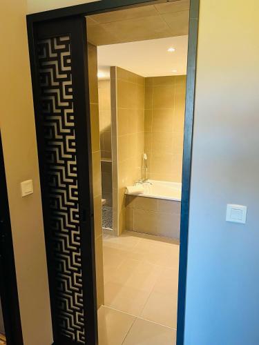 a bathroom with a glass door with a bath tub at L'HOTEL DE LA BOURSE à BAGNOLS-SUR-CEZE in Bagnols-sur-Cèze