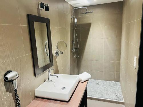 a bathroom with a sink and a shower with a mirror at L'HOTEL DE LA BOURSE à BAGNOLS-SUR-CEZE in Bagnols-sur-Cèze