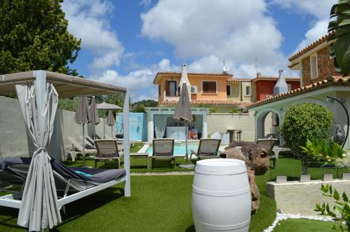 a backyard with chairs and umbrellas and a house at Suimi's Hotel in Villasimius