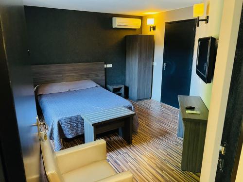 a bedroom with a bed and a couch and a television at L'HOTEL DE LA BOURSE à BAGNOLS-SUR-CEZE in Bagnols-sur-Cèze
