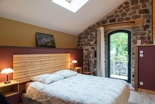 a bedroom with a large bed and a stone wall at Les Balcons de la Terrasse in Arsac-en-Velay
