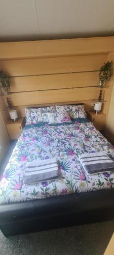 a bed with a floral bedspread and two pillows on it at Diamond Lodge in Millom