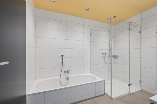 een witte badkamer met een bad en een douche bij The R Apartment Zugerberg - EV Wallbox - Terrasse in Geroldswil