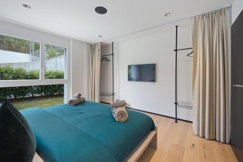 a bedroom with a blue bed and a large window at The R Apartment Zugerberg - EV Wallbox - Terrasse in Geroldswil