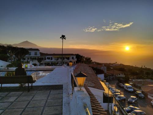 una persona sentada en un banco en un balcón con vistas a la puesta de sol en SweetPearl, en Tacoronte