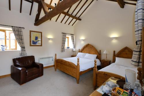 a bedroom with two beds and a chair at Church Farm Lodge in Harrington