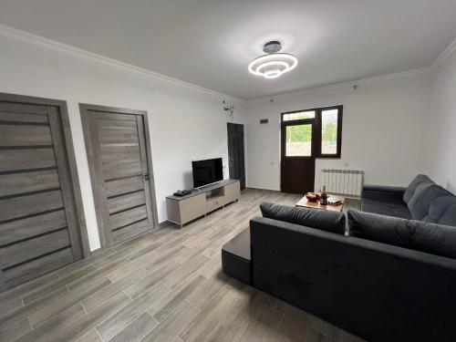 ein Wohnzimmer mit einem schwarzen Sofa und einem TV in der Unterkunft Luysi Garden in Garni