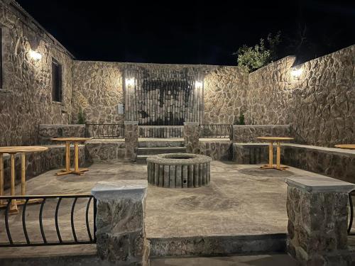 Habitación de piedra con bancos y mesas por la noche en Luysi Garden, en Garni