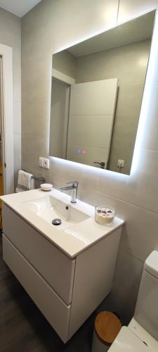 a bathroom with a sink and a large mirror at Apartamento en playa de Laxe in Laxe