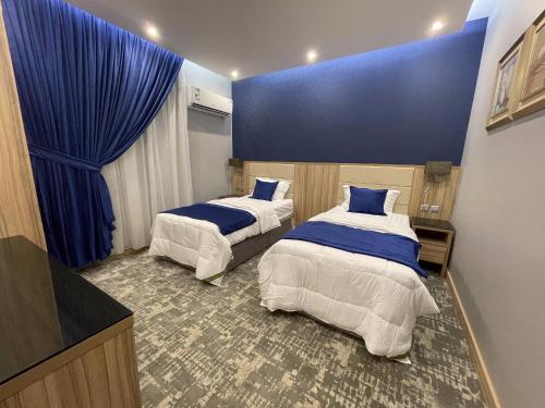 two beds in a room with blue walls and blue curtains at Mehad Stay for Self Check-In Apartment in Jeddah
