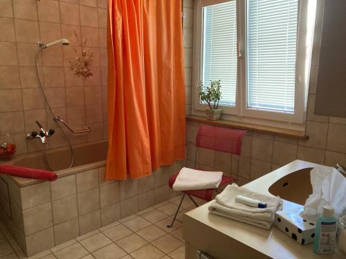einen orangenen Duschvorhang im Bad mit Waschbecken in der Unterkunft Konditor B & B in Frenkendorf