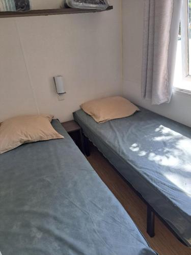 deux lits dans une petite pièce avec une fenêtre dans l'établissement Mobil Home Domaine des Iscles, à La Roque-dʼAnthéron