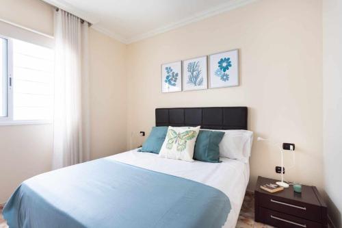 Un dormitorio con una cama azul y blanca y una ventana en La Negrita en San Andrés cerca de la playa y WIFI en Santa Cruz de Tenerife