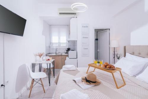 een witte woonkamer met een tafel en een keuken bij Dreamy Delight Studio in Heraklion