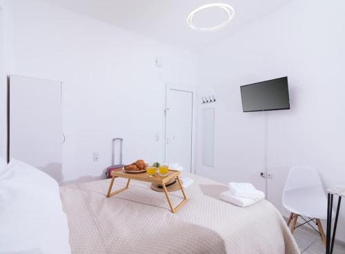 een witte slaapkamer met een tafel op een bed bij Dreamy Delight Studio in Heraklion