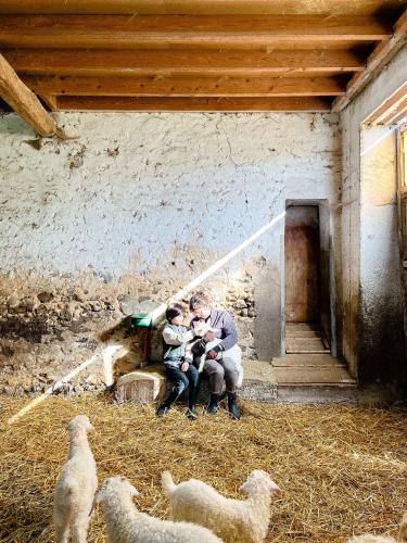 a man and two children and sheep in a barn at Joy Tiny House Perche in Madeleine