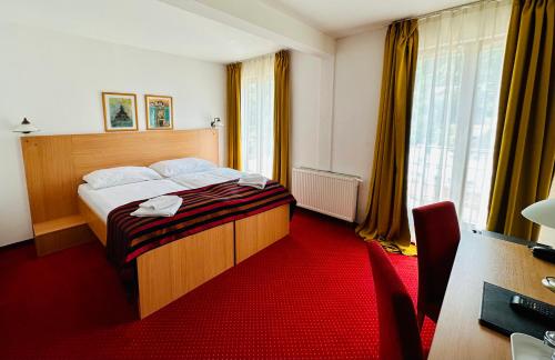 a hotel room with a bed with a red carpet at Hotel & Penzión Grand Matej in Banská Štiavnica