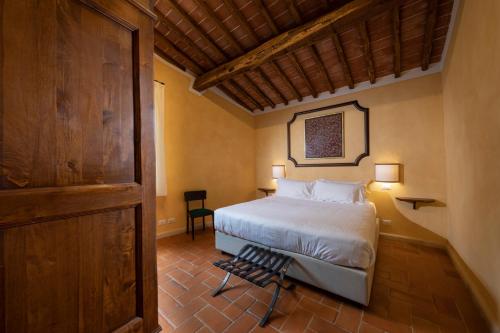 a bedroom with a bed and a chair in a room at BORGO A MONTI di Sotto in Gaiole in Chianti