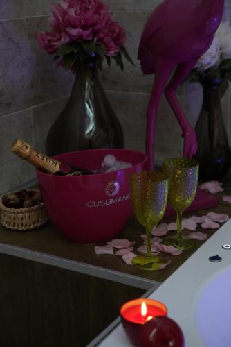 a table with two wine glasses and a pink bowl and flowers at Airport suite in Catania