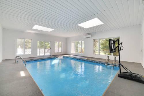- une grande piscine dans une pièce dotée de fenêtres dans l'établissement Spacious 6 Bdrm w/ Private Indoor Pool + VIEWS, à Narrowsburg