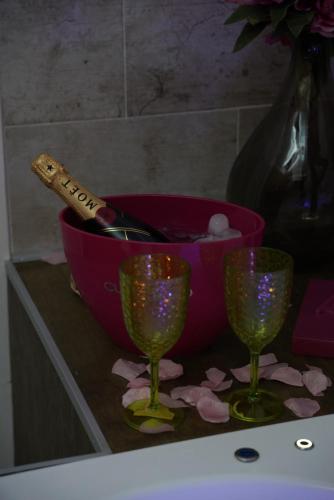 a pink bowl with a bottle of wine and three wine glasses at Airport suite in Catania