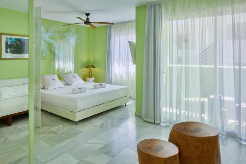 um quarto com uma cama branca e paredes verdes em Tropicana Ibiza Suites - Adults Only em Playa d'en Bossa
