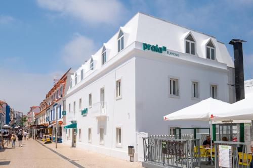 a white building with a sign on it on a street at Praia FLH Hotels Ericeira in Ericeira