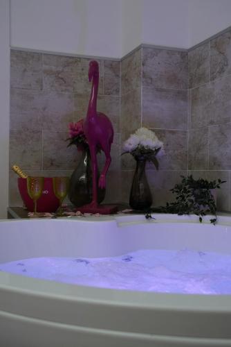 a pink dinosaur statue sitting on top of a bath tub at Airport suite in Catania