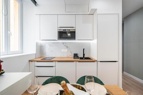 a kitchen with white cabinets and a table and chairs at 2mn Monaco - Luxueux appartement rénové - AS in Beausoleil