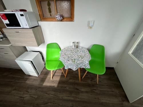 a table and four green chairs in a room at H@M Penzion in Žlutice