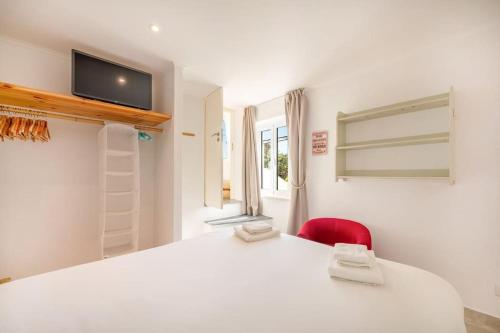 una camera con un letto bianco e una sedia rossa di GuestReady - A special place near the beaches a Colares