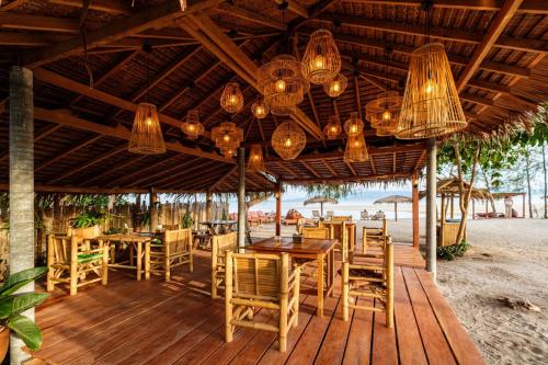 All At Sea Beach Resort في بان تاي: مطعم على الشاطئ به طاولات وكراسي